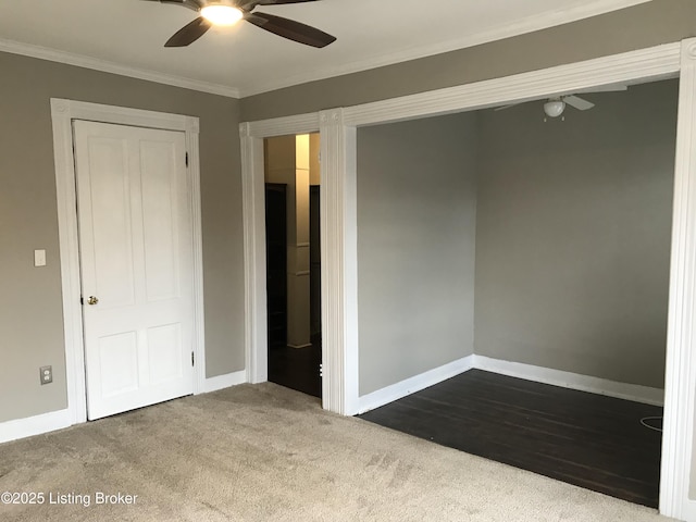 unfurnished bedroom with ceiling fan, carpet, crown molding, and a closet