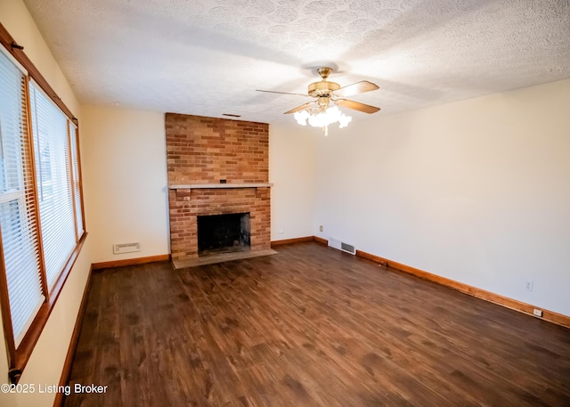 unfurnished living room featuring a fireplace, a textured ceiling, ceiling fan, and dark wood-type flooring