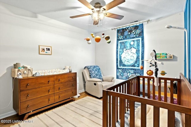 bedroom with a nursery area and ceiling fan