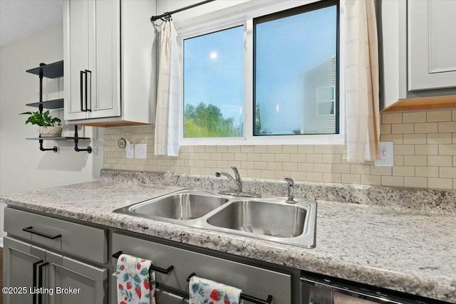 kitchen with decorative backsplash, dishwashing machine, sink, and white cabinets