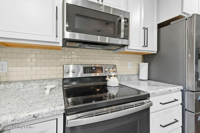 kitchen with decorative backsplash, light stone counters, white cabinetry, and appliances with stainless steel finishes