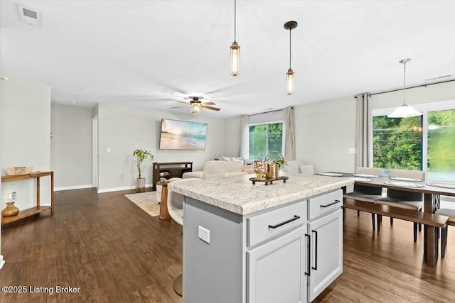 kitchen featuring ceiling fan, dark wood-type flooring, pendant lighting, a center island, and white cabinetry