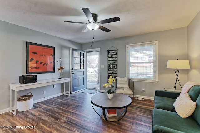 living room with a wealth of natural light, dark wood-type flooring, and ceiling fan