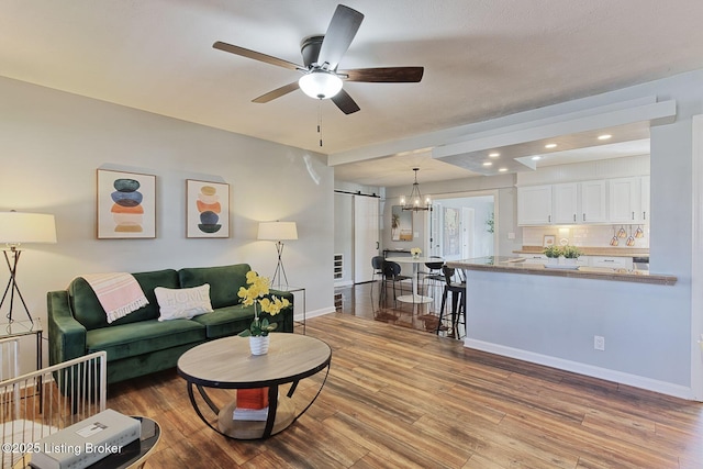 living room with a barn door, ceiling fan, and light hardwood / wood-style flooring