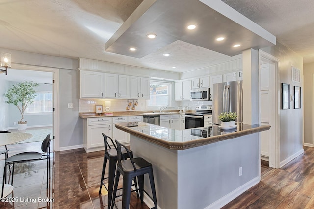 kitchen with white cabinetry, tasteful backsplash, a breakfast bar, and appliances with stainless steel finishes