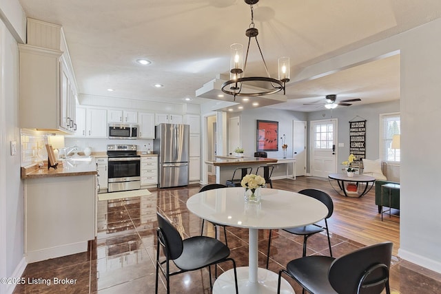 dining room featuring sink and ceiling fan with notable chandelier