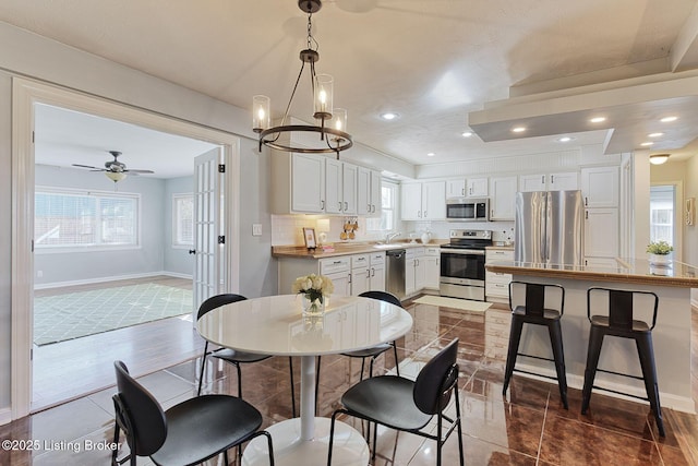 tiled dining area featuring sink, a wealth of natural light, and ceiling fan