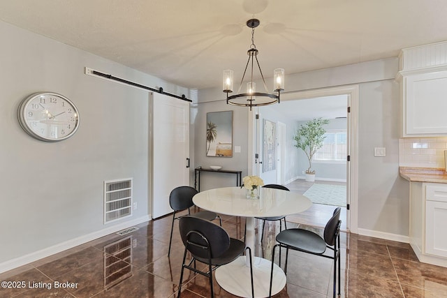 dining area featuring a notable chandelier and a barn door