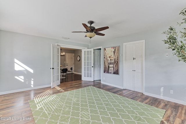 empty room with ceiling fan, dark hardwood / wood-style flooring, and french doors