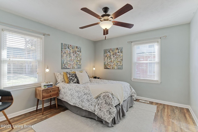 bedroom with multiple windows, hardwood / wood-style flooring, and ceiling fan