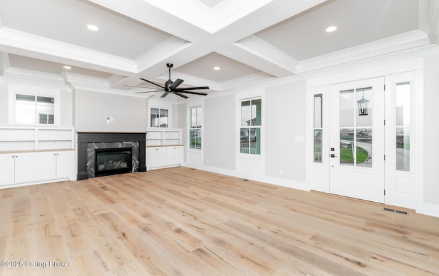 unfurnished living room featuring beam ceiling, ceiling fan, a high end fireplace, and light wood-type flooring