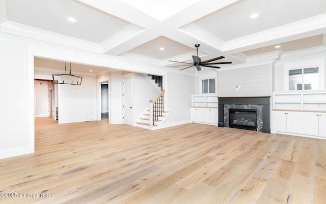 unfurnished living room featuring coffered ceiling, light hardwood / wood-style flooring, ceiling fan, a fireplace, and beam ceiling