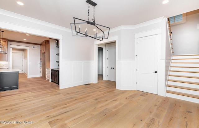 unfurnished dining area with a chandelier, crown molding, and light hardwood / wood-style flooring