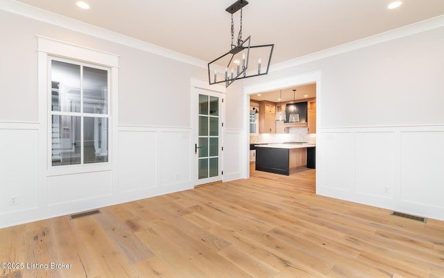 unfurnished dining area with light wood-type flooring and ornamental molding