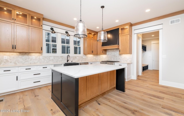 kitchen featuring light stone countertops, custom exhaust hood, sink, a center island, and white cabinetry