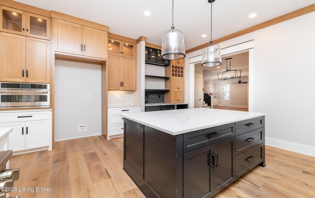 kitchen with light stone countertops, oven, pendant lighting, decorative backsplash, and a kitchen island