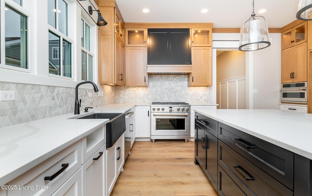 kitchen featuring light stone countertops, appliances with stainless steel finishes, decorative backsplash, pendant lighting, and light hardwood / wood-style flooring