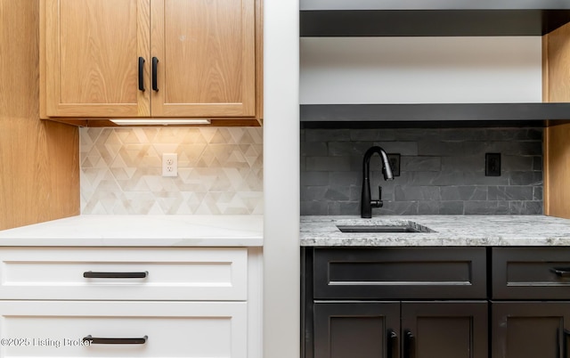 kitchen with decorative backsplash, light stone counters, and sink