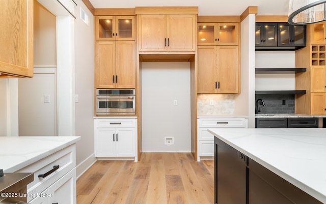 kitchen featuring light hardwood / wood-style floors, stainless steel oven, light stone countertops, and tasteful backsplash