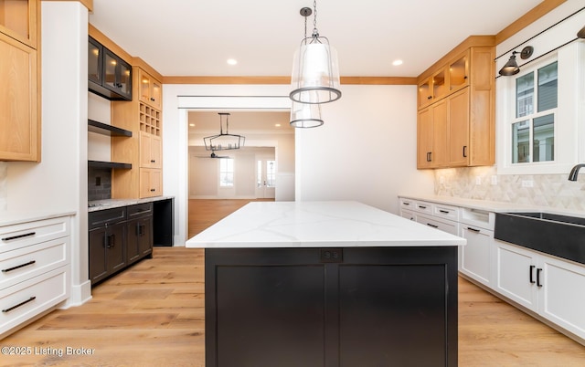 kitchen with pendant lighting, a center island, light stone countertops, and backsplash