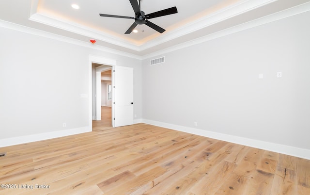 unfurnished room featuring ceiling fan, a raised ceiling, light wood-type flooring, and crown molding