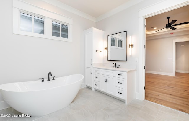 bathroom featuring ceiling fan, ornamental molding, a tub, and vanity