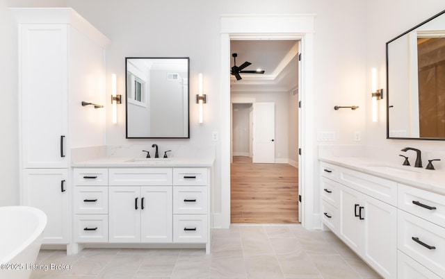 bathroom featuring vanity, tile patterned floors, a raised ceiling, ceiling fan, and a tub to relax in