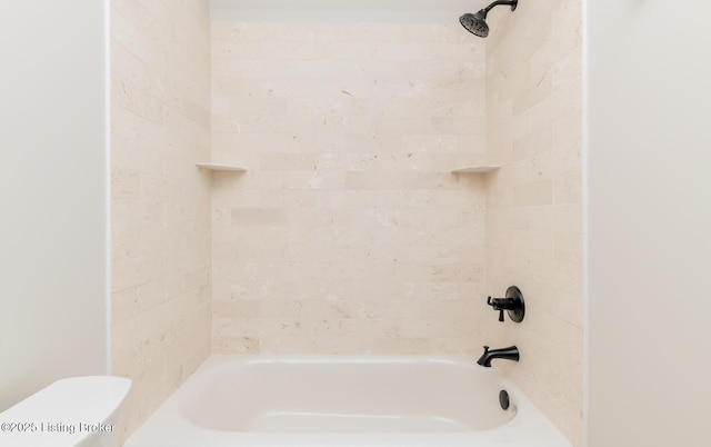 bathroom featuring toilet and tiled shower / bath