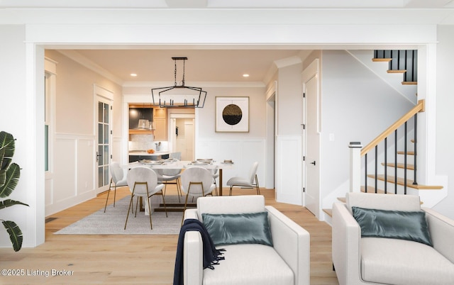 dining space with crown molding, light hardwood / wood-style floors, and a notable chandelier