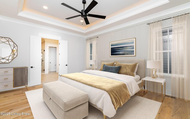 bedroom with a tray ceiling, ceiling fan, and light hardwood / wood-style flooring