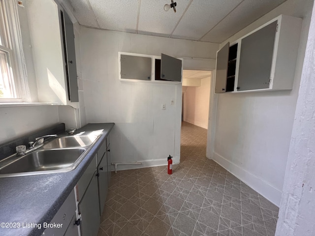 kitchen with a drop ceiling, sink, and gray cabinets