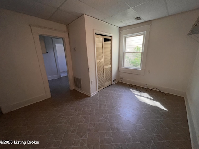 unfurnished bedroom with a paneled ceiling and a closet