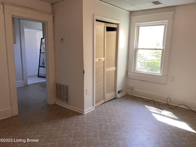 unfurnished bedroom featuring a paneled ceiling and a closet