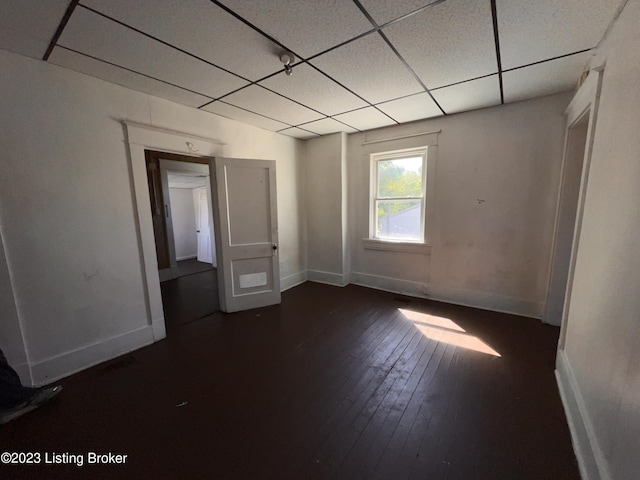 spare room featuring dark hardwood / wood-style floors and a drop ceiling