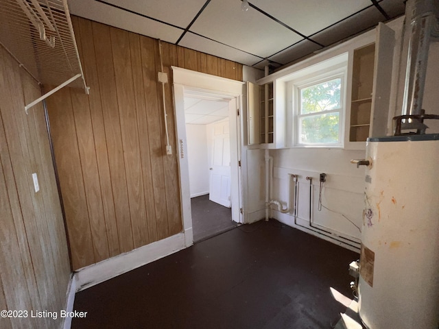 clothes washing area with wooden walls and water heater