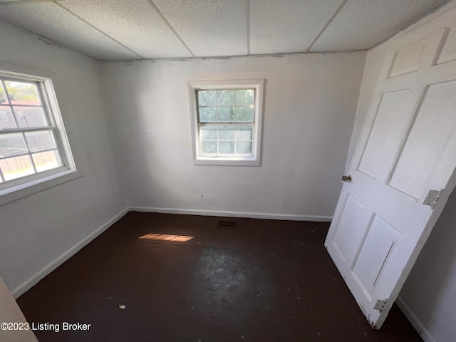 empty room featuring a wealth of natural light and a drop ceiling