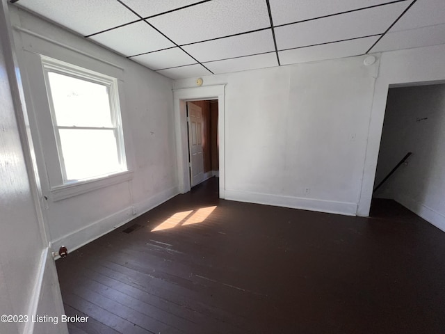 empty room featuring a paneled ceiling and dark hardwood / wood-style floors