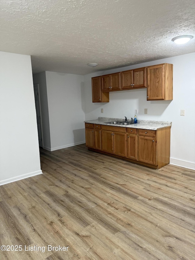 kitchen featuring sink, a textured ceiling, and light hardwood / wood-style floors