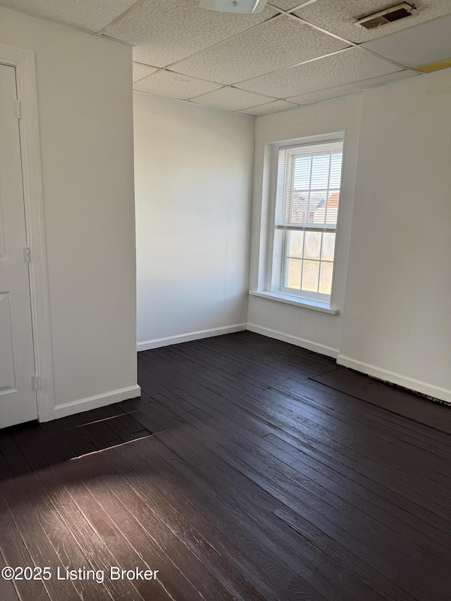 spare room featuring a drop ceiling and dark wood-type flooring