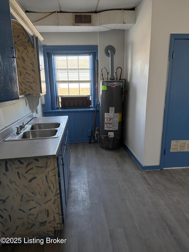 kitchen featuring a drop ceiling, dark hardwood / wood-style flooring, sink, and gas water heater