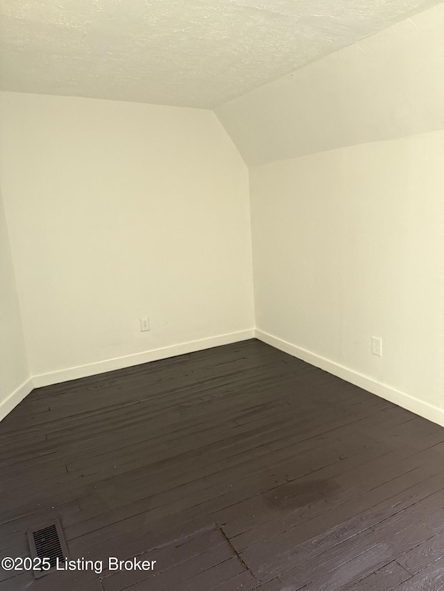 bonus room with lofted ceiling, dark hardwood / wood-style flooring, and a textured ceiling