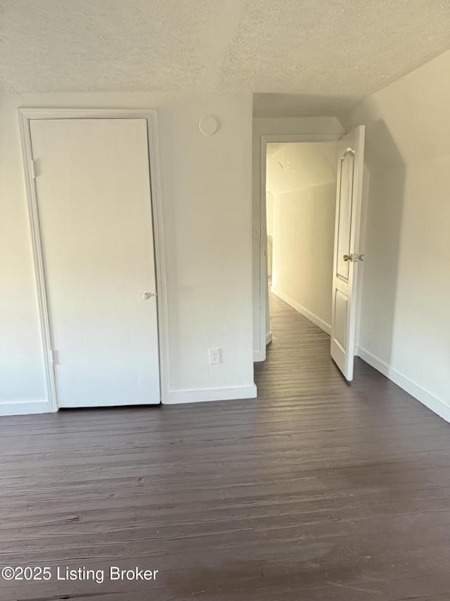 spare room featuring dark hardwood / wood-style flooring and a textured ceiling