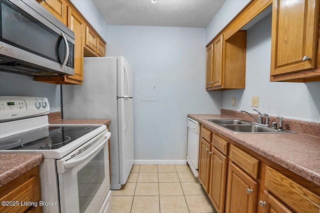 kitchen featuring a textured ceiling, white appliances, sink, and light tile patterned floors