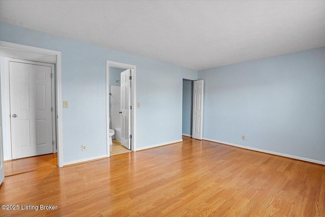 unfurnished bedroom featuring light wood-type flooring and ensuite bath