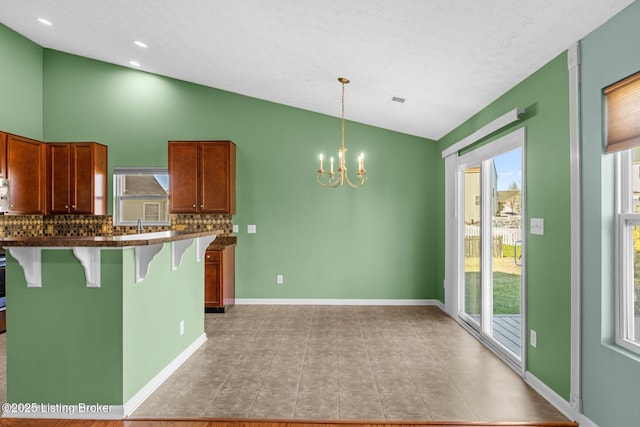 kitchen featuring a notable chandelier, pendant lighting, decorative backsplash, a kitchen breakfast bar, and a textured ceiling