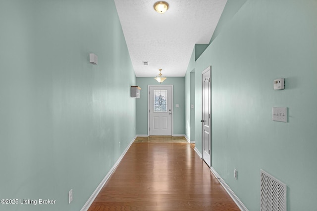 doorway to outside featuring a textured ceiling and hardwood / wood-style flooring