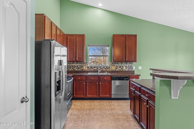 kitchen with appliances with stainless steel finishes, tasteful backsplash, sink, vaulted ceiling, and light tile patterned floors