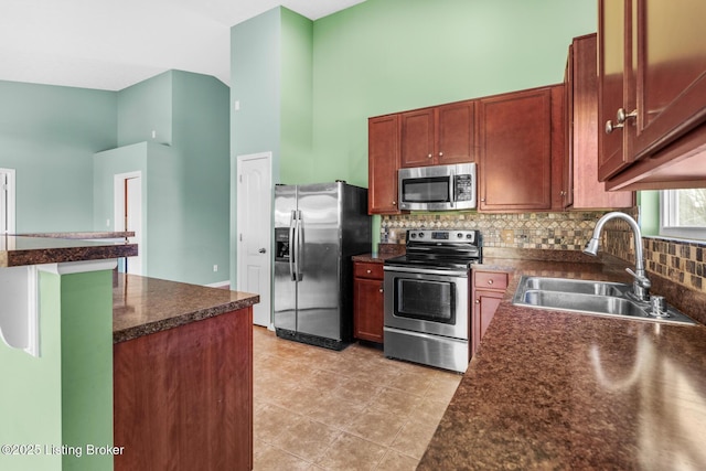 kitchen with a high ceiling, appliances with stainless steel finishes, tasteful backsplash, sink, and light tile patterned floors