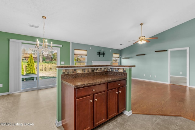 kitchen with lofted ceiling, ceiling fan with notable chandelier, and pendant lighting