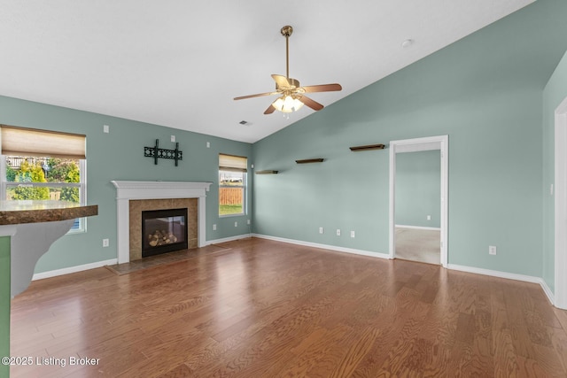 unfurnished living room with vaulted ceiling, ceiling fan, a high end fireplace, and hardwood / wood-style flooring